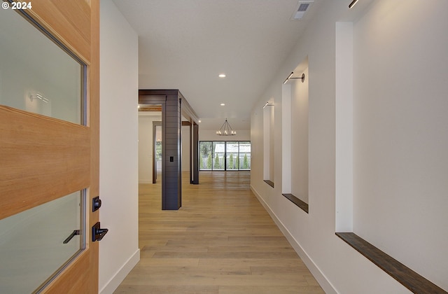 corridor featuring light hardwood / wood-style flooring and a notable chandelier