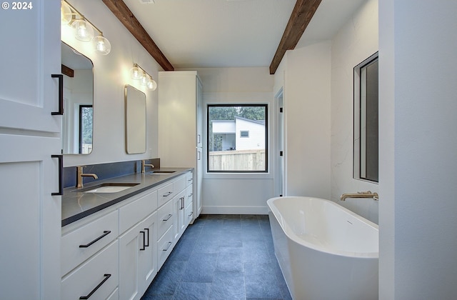 bathroom featuring beamed ceiling, vanity, and a tub