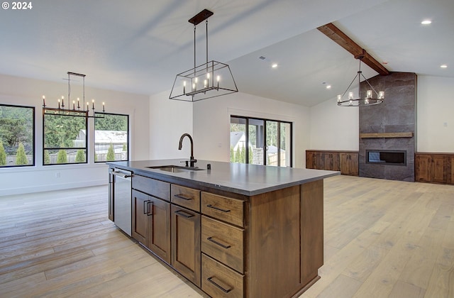 kitchen with sink, dishwasher, lofted ceiling with beams, a kitchen island with sink, and a fireplace