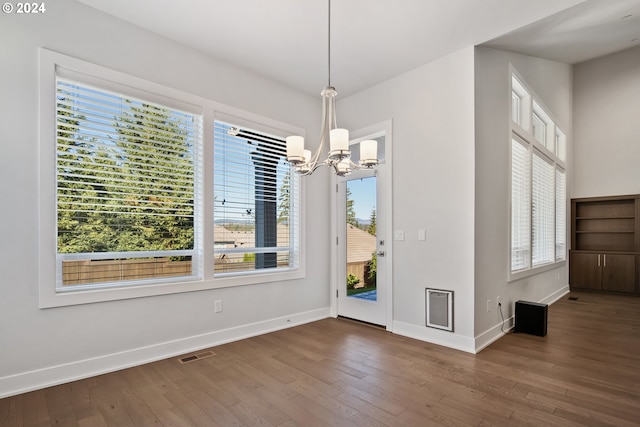 unfurnished dining area with a chandelier and dark wood-type flooring