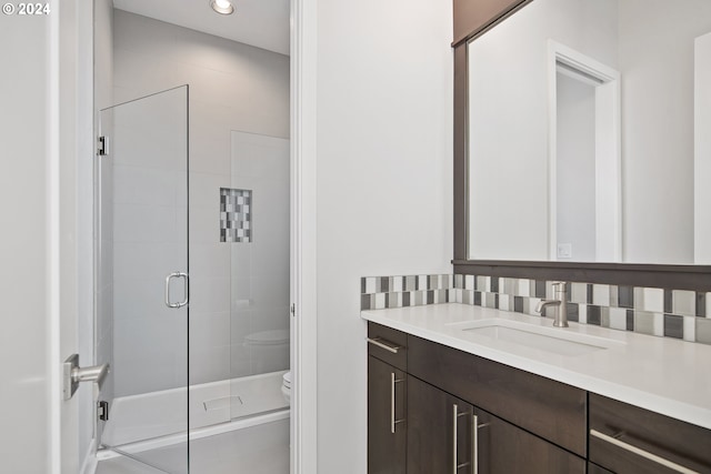 bathroom featuring an enclosed shower, backsplash, vanity, and toilet