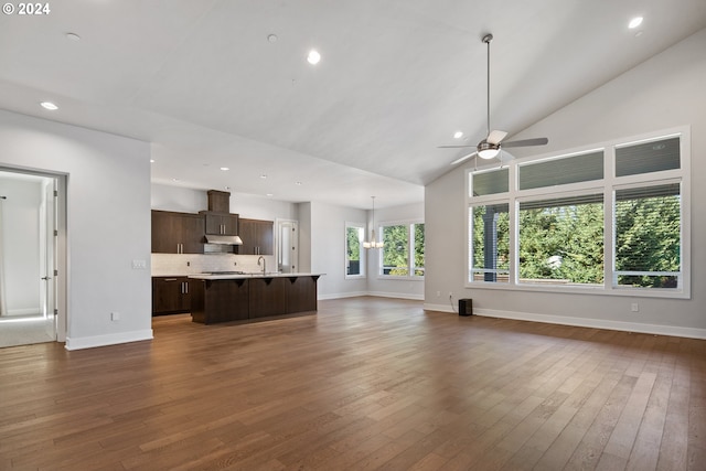 unfurnished living room featuring sink, ceiling fan with notable chandelier, dark wood-type flooring, and high vaulted ceiling