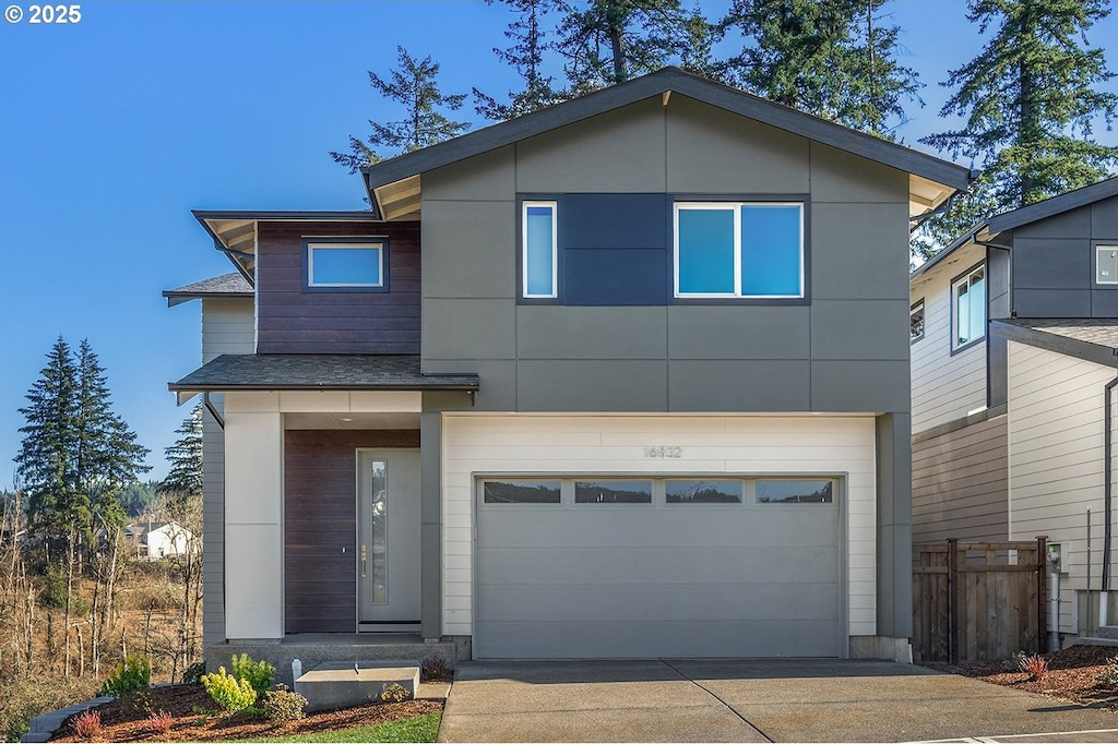 contemporary house featuring concrete driveway, fence, and a garage