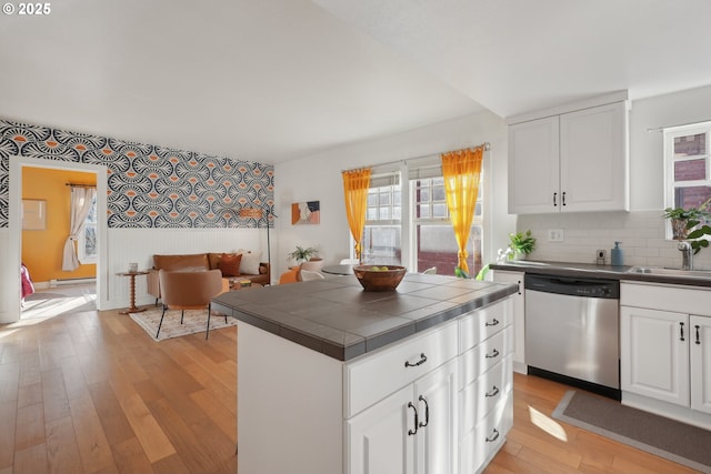 kitchen with white cabinets, tile countertops, stainless steel dishwasher, and sink