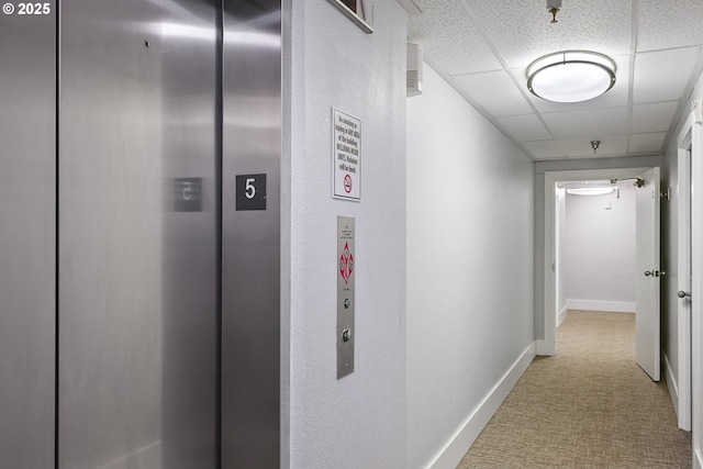 corridor featuring a paneled ceiling and elevator