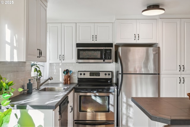 kitchen featuring sink, appliances with stainless steel finishes, tasteful backsplash, white cabinetry, and kitchen peninsula