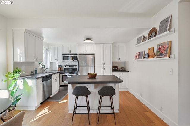 kitchen with appliances with stainless steel finishes, tasteful backsplash, a breakfast bar, sink, and white cabinetry