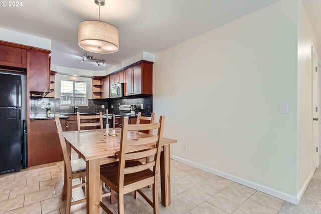 kitchen featuring light tile patterned floors, stainless steel appliances, decorative light fixtures, and backsplash