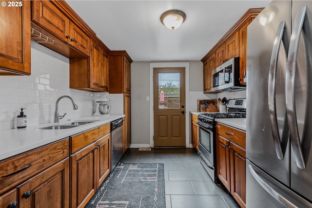 kitchen featuring dark tile patterned floors, appliances with stainless steel finishes, sink, and backsplash