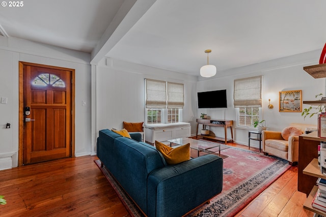 living room featuring a healthy amount of sunlight, hardwood / wood-style floors, and beam ceiling