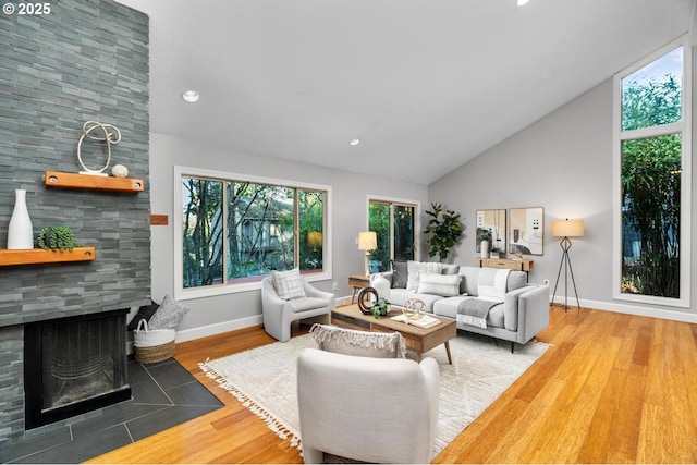 living room featuring wood-type flooring, high vaulted ceiling, and a fireplace