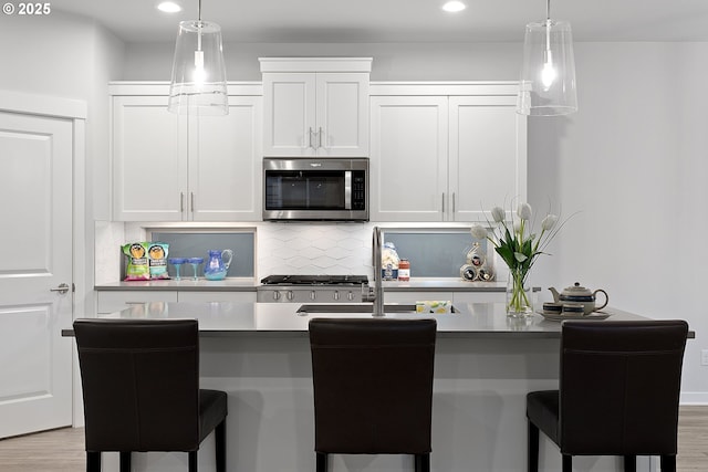 kitchen with backsplash, a breakfast bar, white cabinets, and pendant lighting