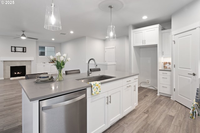 kitchen featuring dishwasher, a center island with sink, white cabinetry, and sink