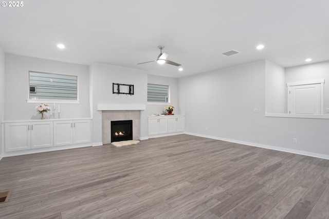 unfurnished living room with ceiling fan, a fireplace, and light hardwood / wood-style flooring