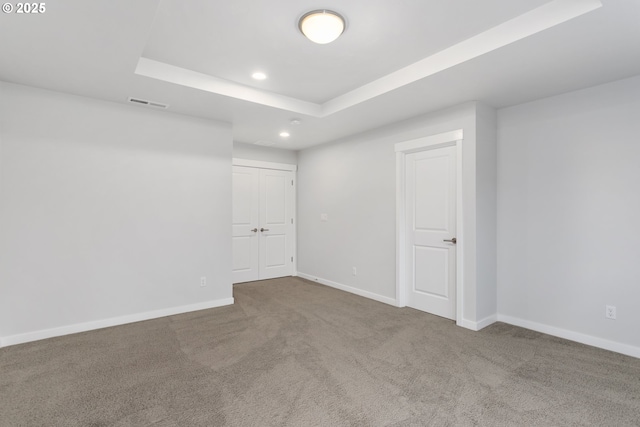 carpeted empty room with a raised ceiling