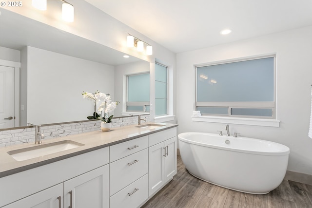 bathroom featuring wood-type flooring, vanity, tasteful backsplash, and a bathing tub