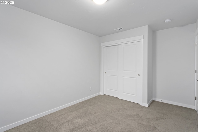 unfurnished bedroom with light carpet and a closet