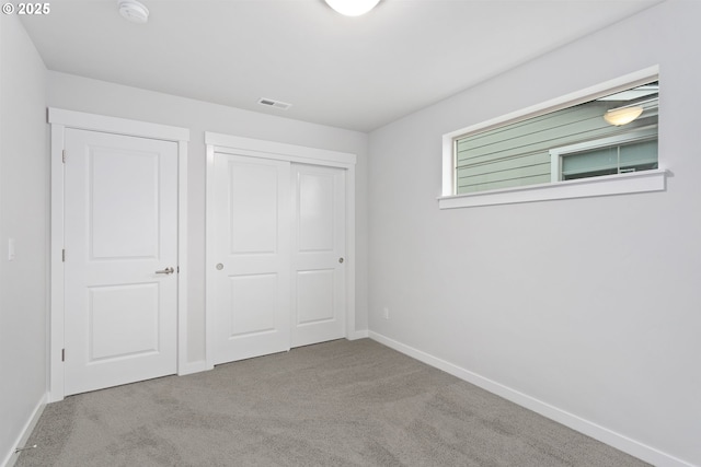 unfurnished bedroom with light carpet and a closet