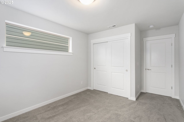 unfurnished bedroom with light colored carpet and a closet