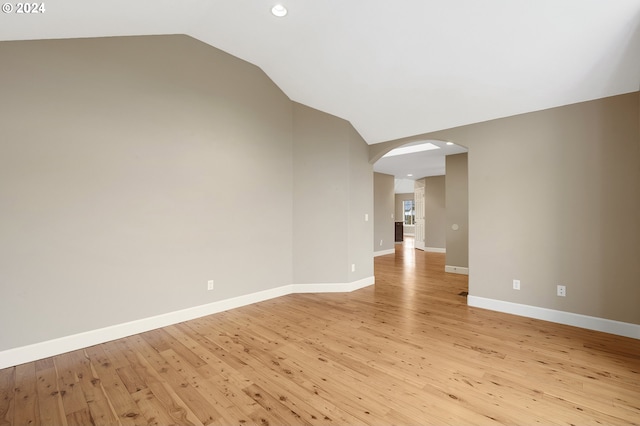 spare room featuring light wood-type flooring and vaulted ceiling