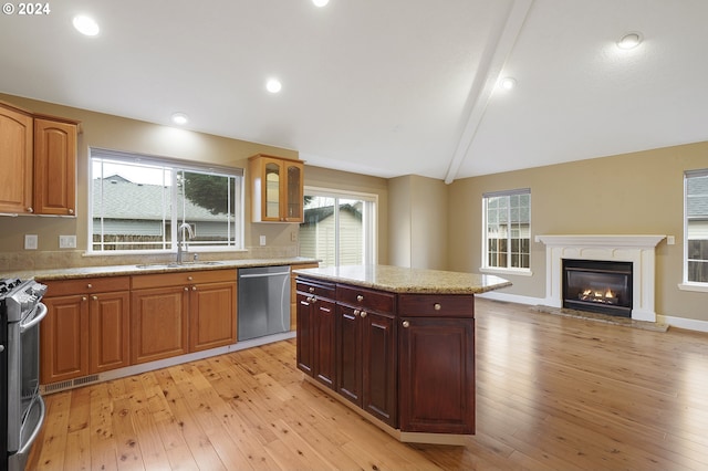 kitchen featuring light wood-type flooring, stainless steel appliances, sink, lofted ceiling with beams, and a kitchen island