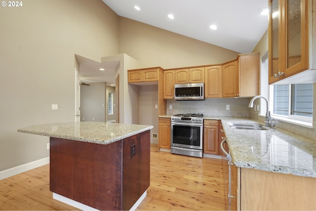 kitchen with light stone counters, light wood-type flooring, sink, and appliances with stainless steel finishes