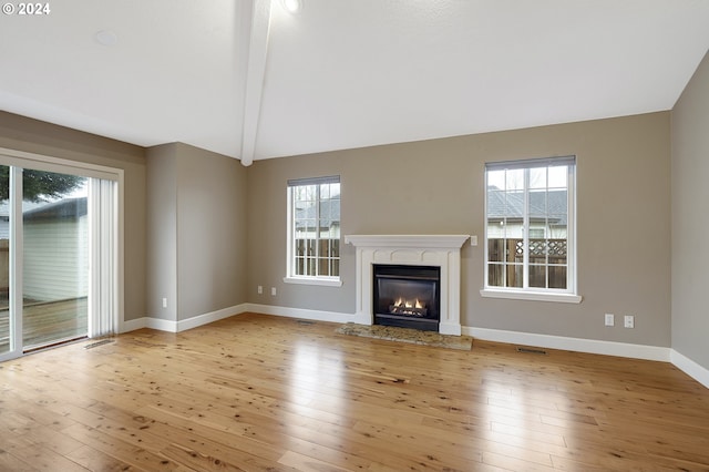 unfurnished living room featuring lofted ceiling with beams, light hardwood / wood-style floors, and a wealth of natural light