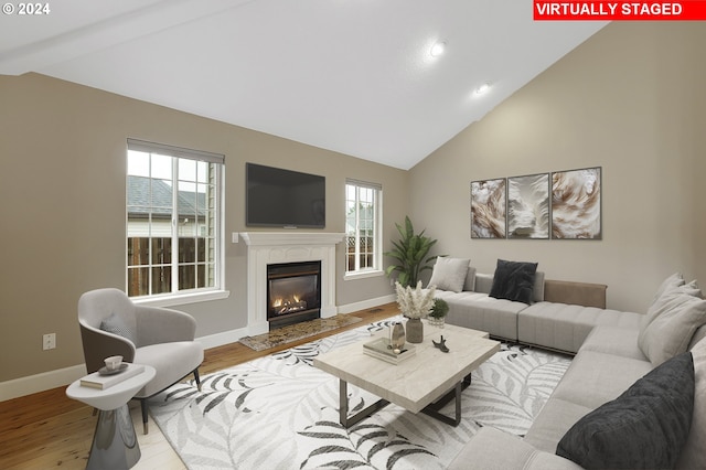 living room with beamed ceiling, high vaulted ceiling, light wood-type flooring, and a wealth of natural light