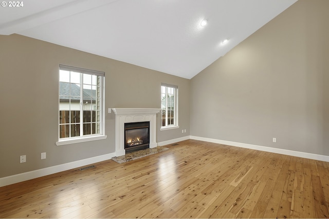 unfurnished living room featuring light hardwood / wood-style flooring, beamed ceiling, and high vaulted ceiling