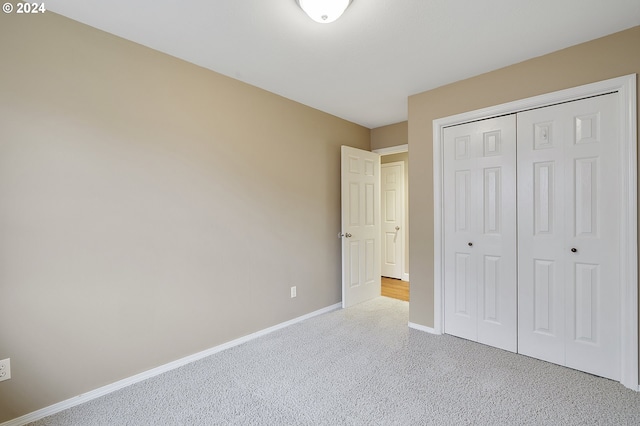 unfurnished bedroom with a closet and light colored carpet