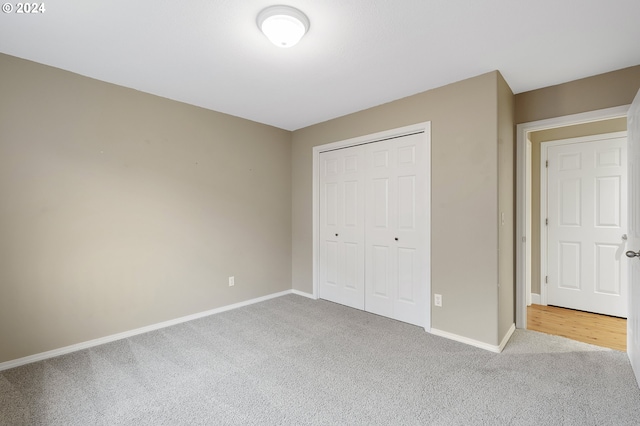 unfurnished bedroom featuring light carpet and a closet