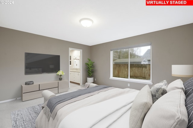 bedroom featuring ensuite bathroom and light carpet