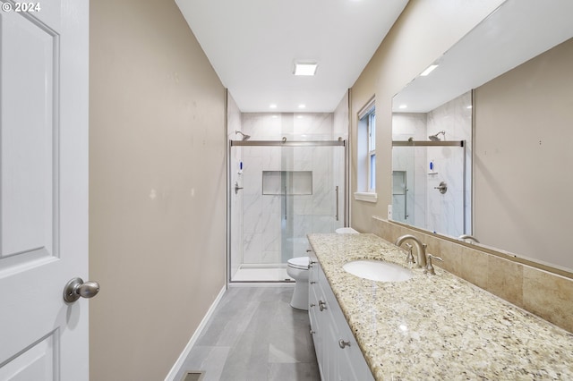 bathroom featuring vanity, toilet, and a shower with shower door