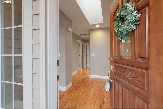 corridor with a skylight and light hardwood / wood-style floors