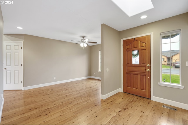 entryway featuring ceiling fan, light wood-type flooring, a wealth of natural light, and a skylight