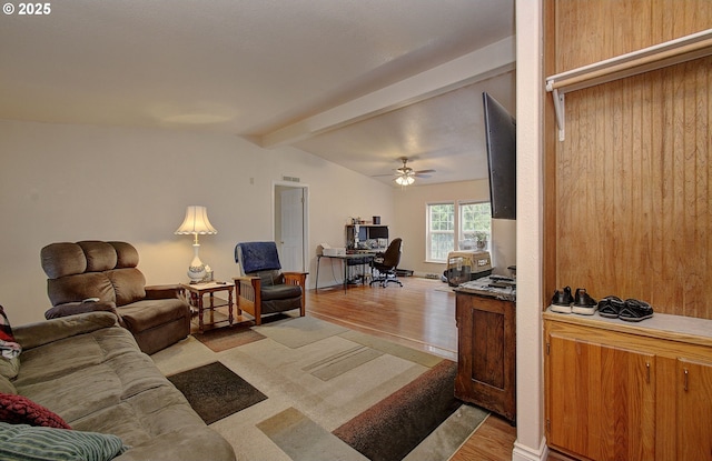 living room featuring ceiling fan, light wood-type flooring, and vaulted ceiling with beams