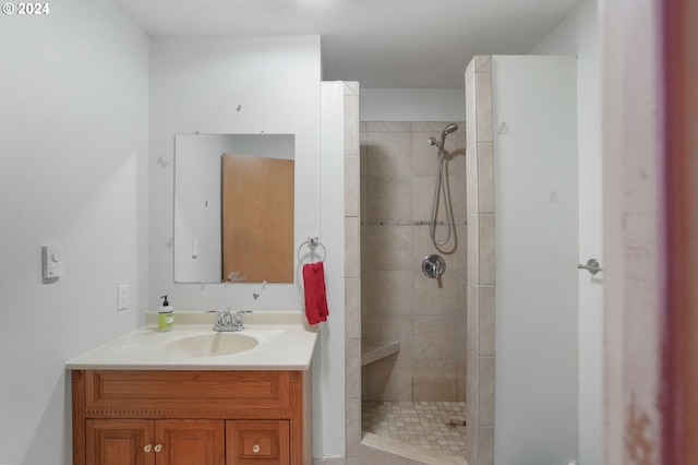 bathroom with a tile shower and vanity