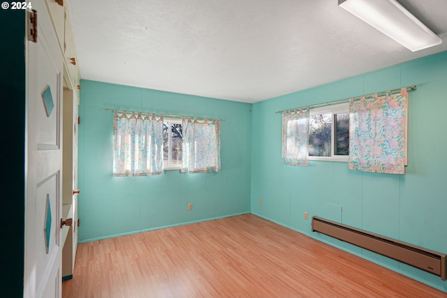 spare room featuring hardwood / wood-style floors, a textured ceiling, and a baseboard radiator