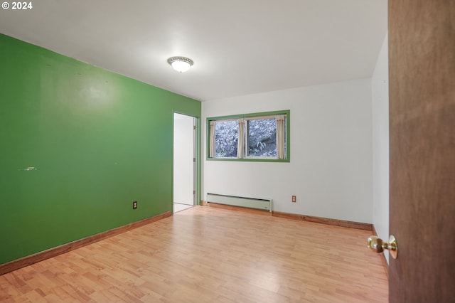 empty room featuring light wood-type flooring and baseboard heating