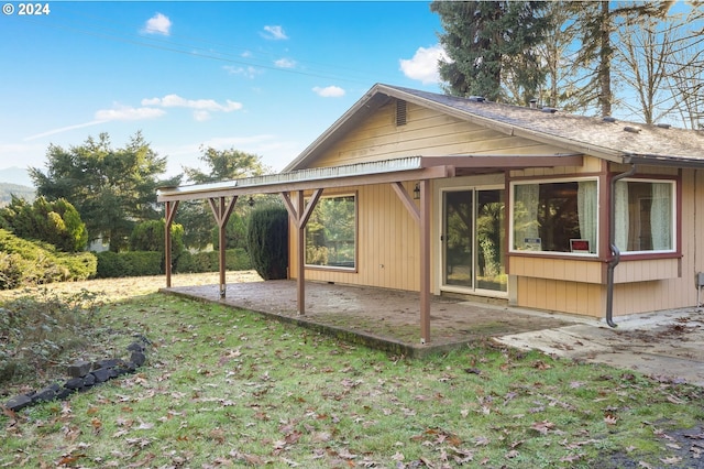 back of property featuring a patio area and a lawn