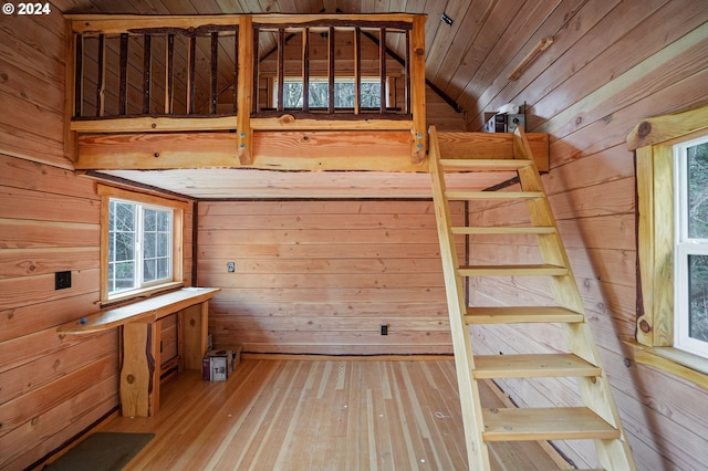 stairway with lofted ceiling, wood-type flooring, and wooden walls