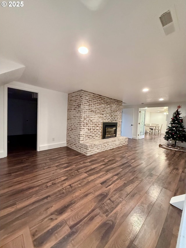 unfurnished living room featuring dark wood-type flooring and a fireplace