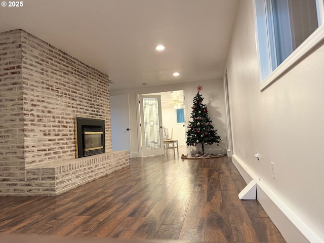 unfurnished living room featuring a brick fireplace and dark hardwood / wood-style flooring