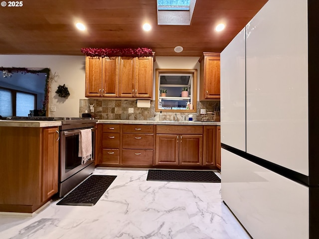 kitchen featuring gas stove, a skylight, decorative backsplash, sink, and wooden ceiling