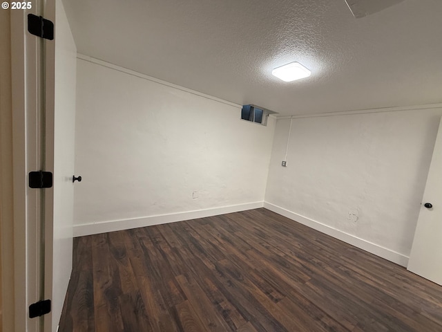 empty room with a textured ceiling and dark hardwood / wood-style floors