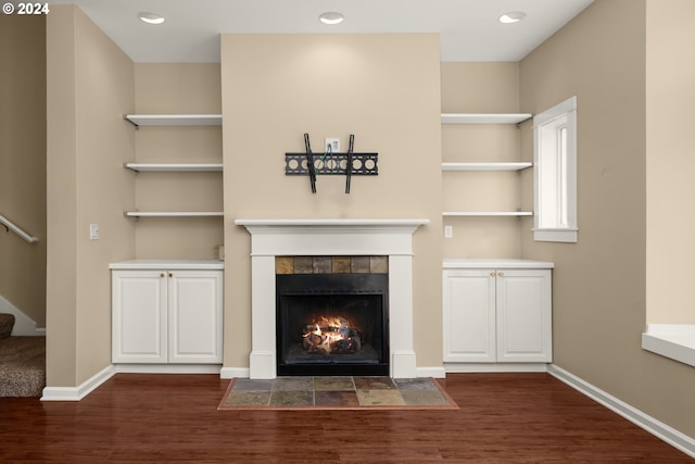 unfurnished living room featuring built in shelves, dark hardwood / wood-style flooring, and a fireplace