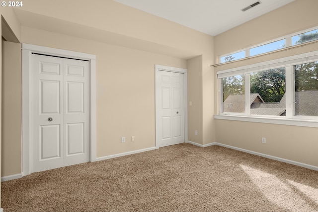 unfurnished bedroom with carpet flooring and two closets