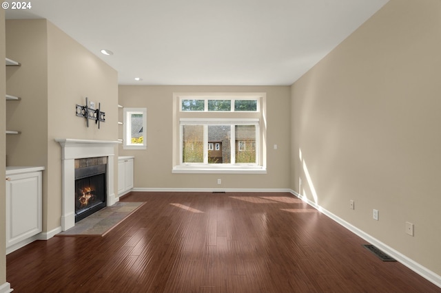 unfurnished living room with dark wood-type flooring and a tiled fireplace