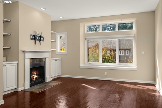 unfurnished living room with plenty of natural light, dark hardwood / wood-style flooring, built in features, and a fireplace