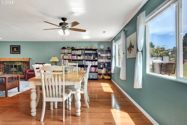 dining space featuring ceiling fan, a fireplace, and wood-type flooring